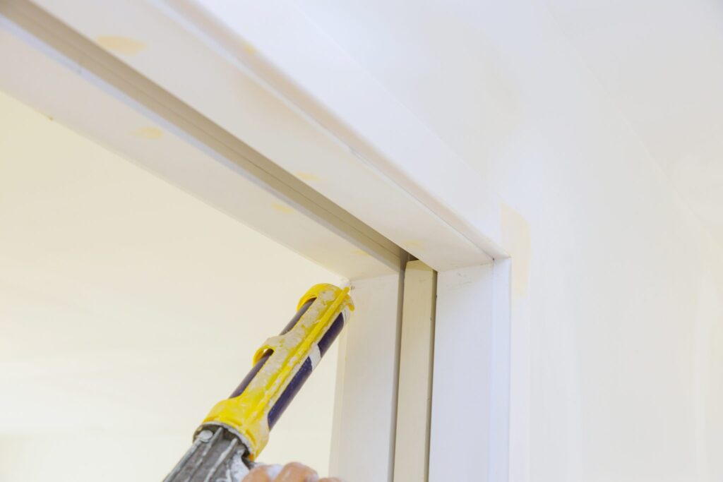 Applying silicone on of molding door trim with caulking gun tool