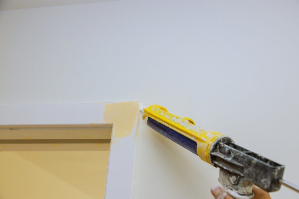 Worker hands on applying silicone sealant with caulking gun